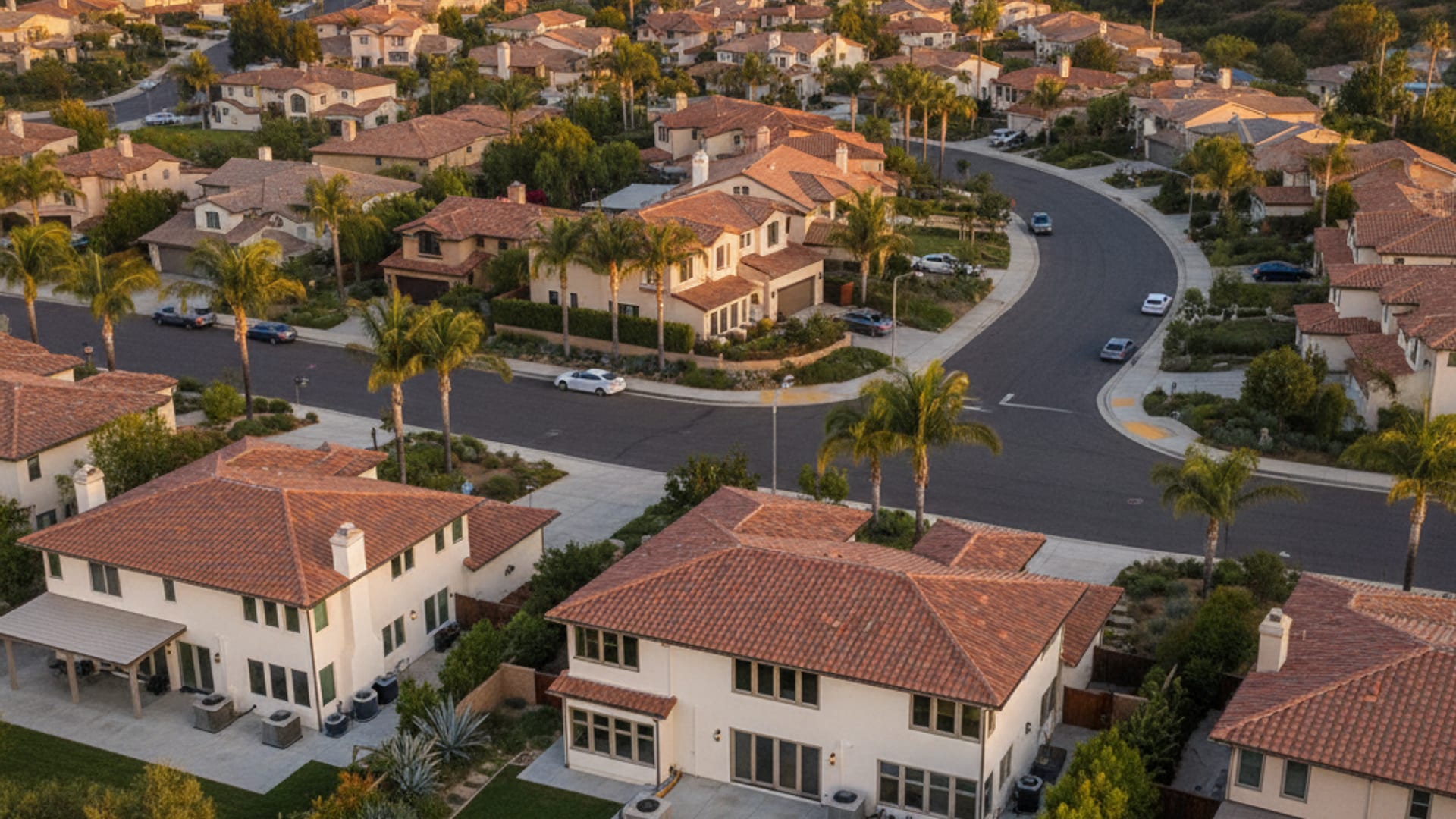 Aerial view of a San Diego County residential neighborhood with rooftop solar arrays visible across stucco homes at golden hour
